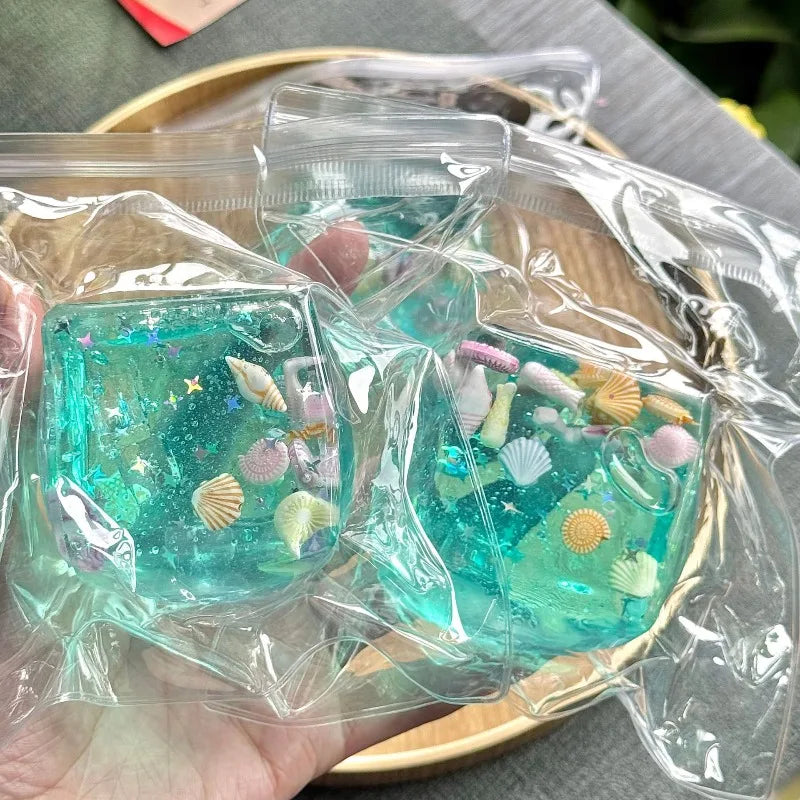 Two clear plastic packages containing blue jelly treats with sea-themed decorations on a wooden surface.