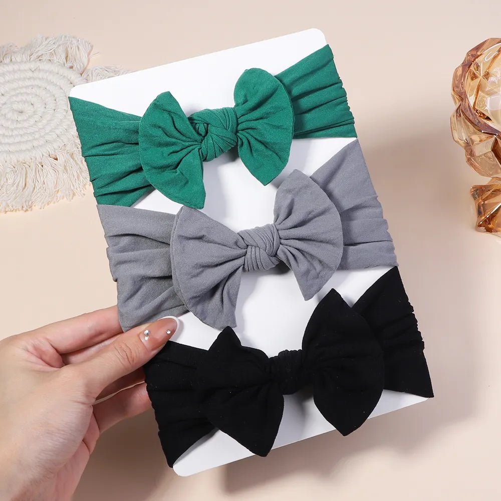 Three colorful hair bows on a white box held by a hand.