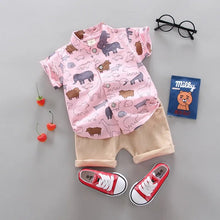 Children's outfit with pink shirt and shorts, red sneakers, and small items 