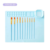 Set of paint brushes on a blue silicone mat with a clear plastic cover.