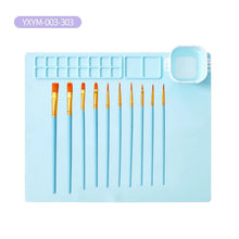 Set of paint brushes on a blue silicone mat with a clear plastic cover. (option 2)