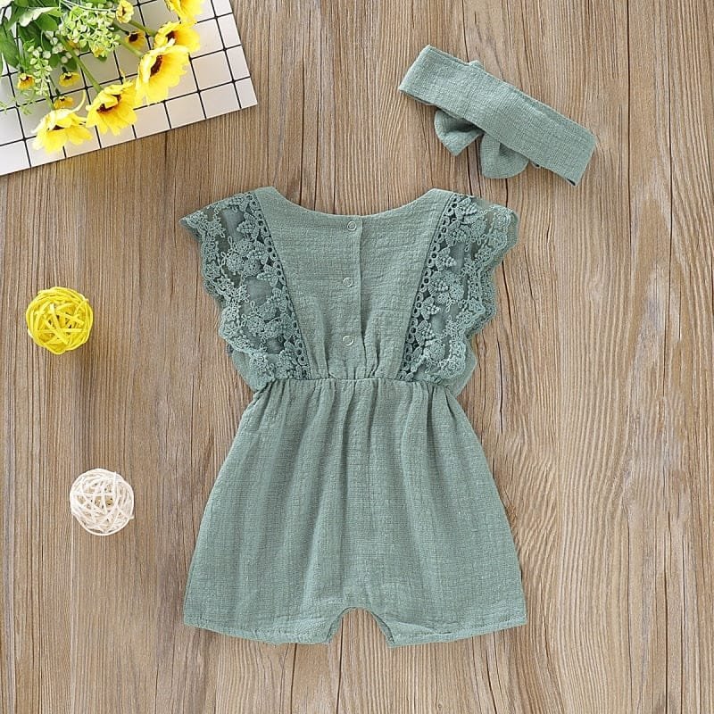 Summer Baby Girl Romper in green with lace trim styled with props for nursery photos and gift presentation.