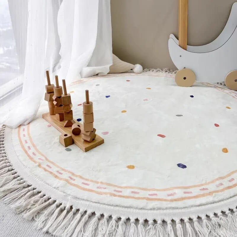 Round white rug with colorful polka dots and tassels, featuring a wooden toy on top.