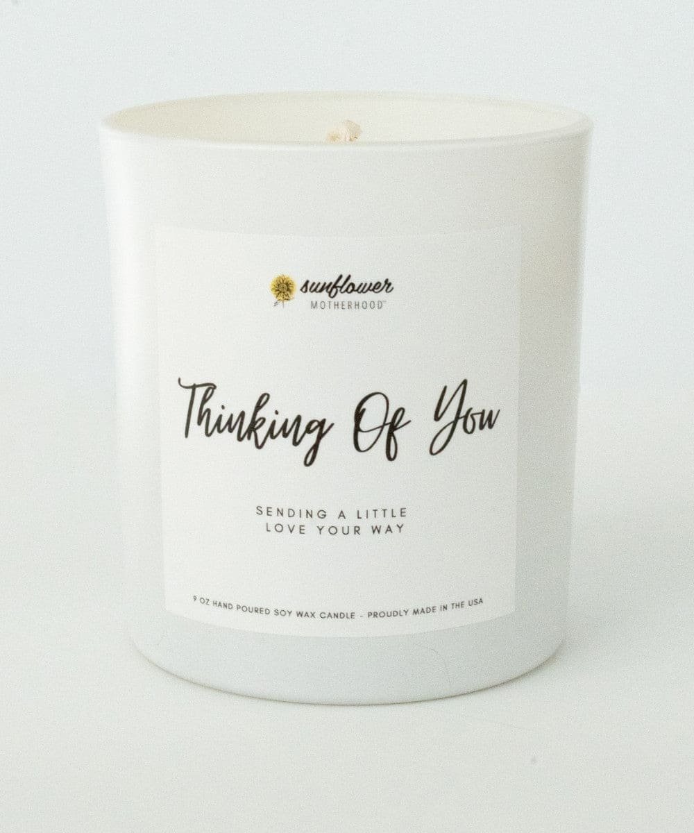 White candle with a label reading 'Thinking Of You' 