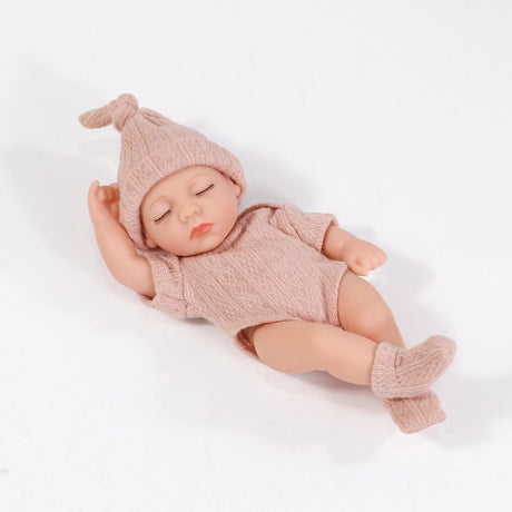 Baby doll in pink knitted outfit on a white background