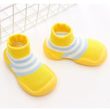 Pair of yellow baby shoes with blue stripes on a white background