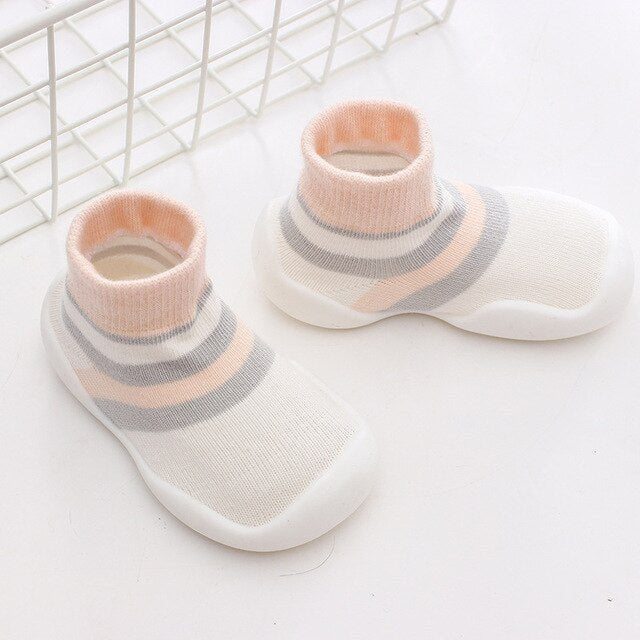 Pair of baby shoes with pink and gray striped tops on a white background