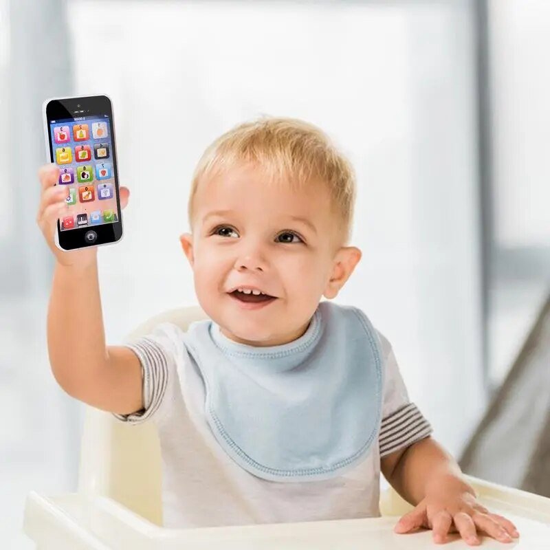 Toddler holding a learning cellphone toy while wearing a bib during early educational playtime.