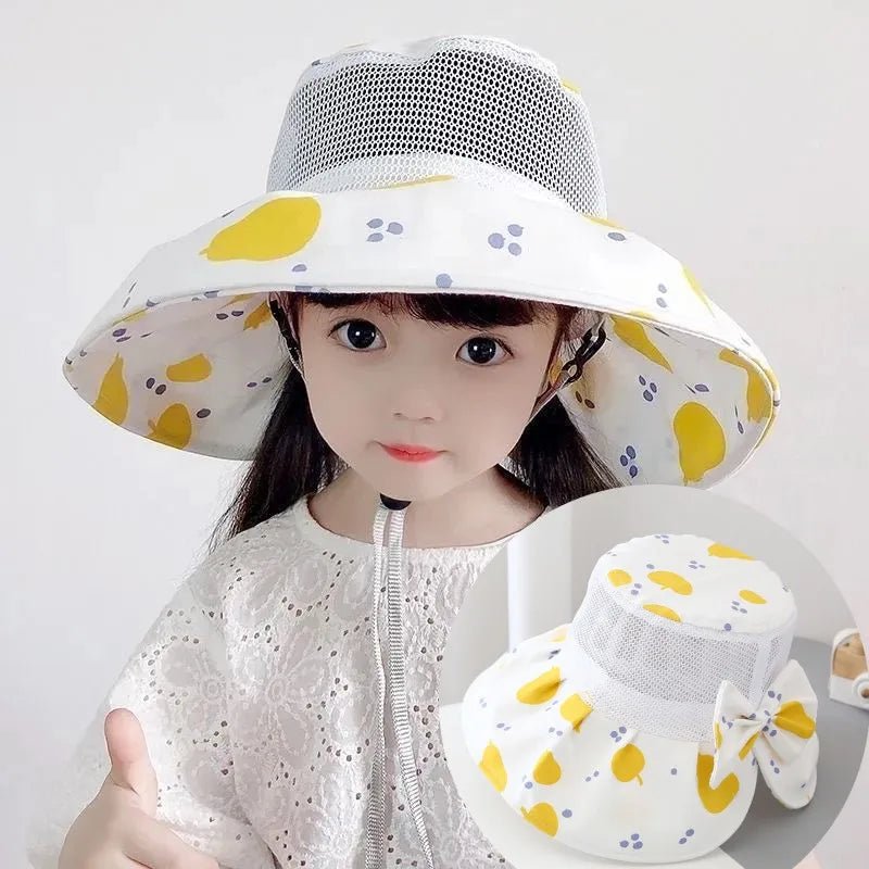 Child wearing a white sun hat with yellow patterns, holding a matching bag 