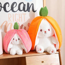 Two carrot rabbit soft toys tucked inside fruit-shaped plush bags for peekaboo play and toddler entertainment.