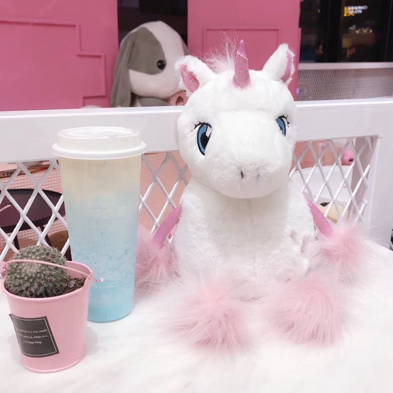 Plush unicorn toy with a gradient cup and small plant in a pink pot.