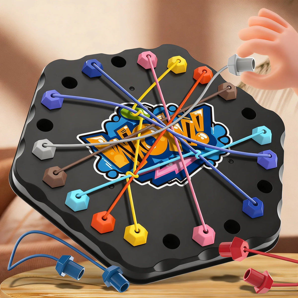 Hand pulling a grey cord from a tangle of colorful elastic cords on a black hexagonal game board
