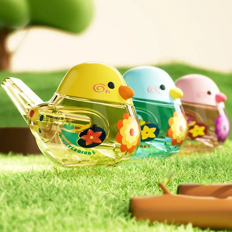 Yellow, blue and pink water bird whistles lined up on grass