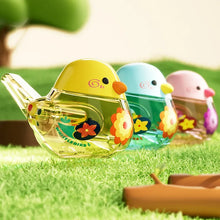 Yellow, blue and pink water bird whistles lined up on grass