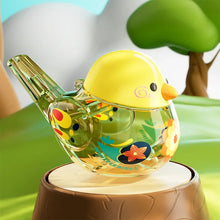 Yellow water bird whistle on a tree stump with a green tree behind it