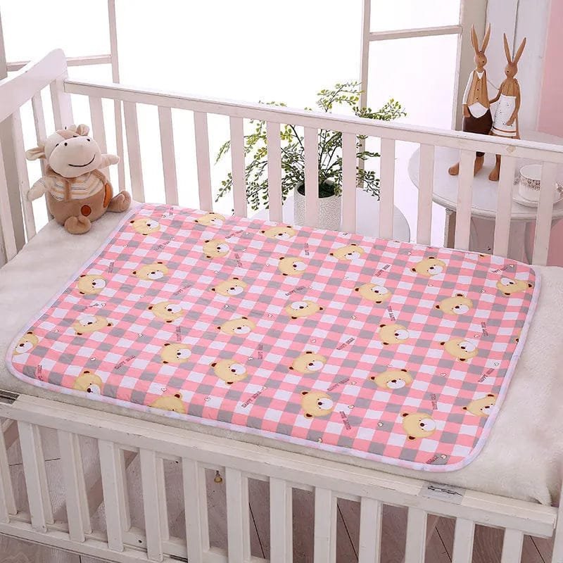 Pink checkered mat with cartoon duck design on a crib