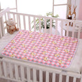 Pink checkered mat with cartoon duck design on a crib