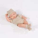 Newborn baby doll wearing a striped outfit and hat on a white background