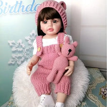 Waterproof silicone Reborn Doll with curly hair in a pink knit outfit with bear toy for bathing, cuddling, and display.