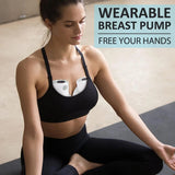 Woman wearing a black sports bra with a wearable breast pump, sitting on a mat.