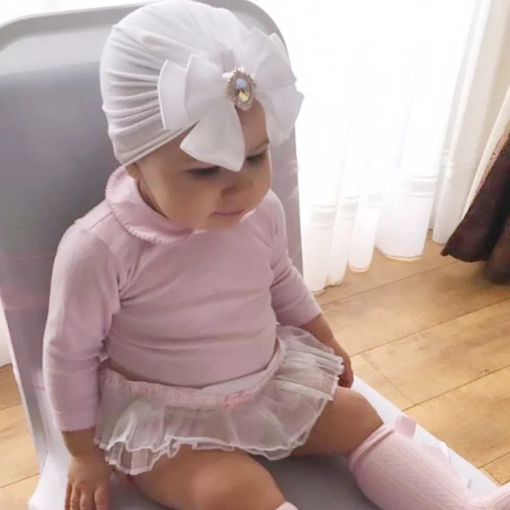 White baby turban cap styled with a pink outfit for newborn photos, family visits, and everyday dressing.