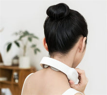 White electric neck massager worn at home for easing stiff shoulders after desk work, driving, and childcare.