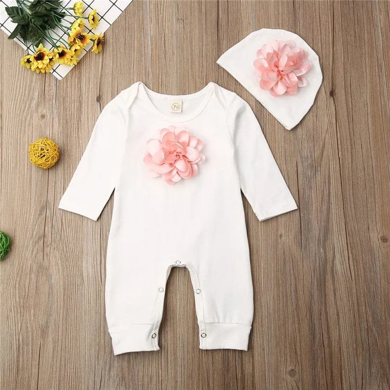 White floral newborn jumpsuit and hat set styled as a gift display, a cotton outfit for showers and homecomings.