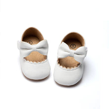 White infant Mary Janes with bow detail and non-slip rubber outsole for first steps.