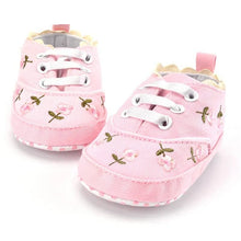 Close-up of the floral embroidery on the white lace baby girl shoes, a dressy prewalker for parties and photo sessions.