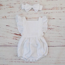 White organic cotton ruffle romper and bow headband, a fresh photo outfit for newborn milestones and gifting.