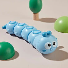Blue wind-up caterpillar toy with big eyes on a beige background
