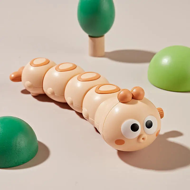 Light orange wind-up caterpillar toy with big eyes on a beige background