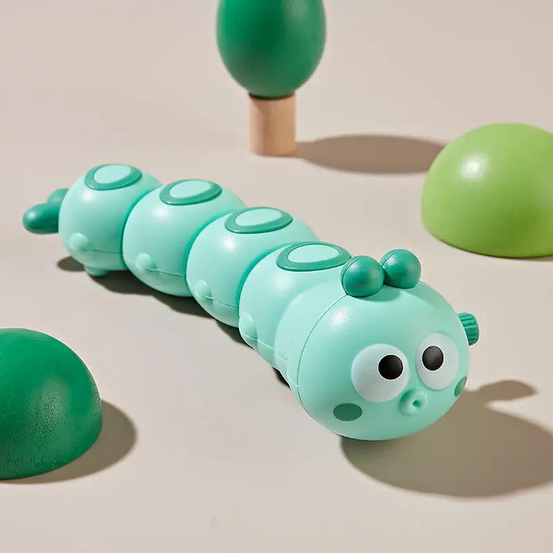 Mint green wind-up caterpillar toy with big eyes on a beige background