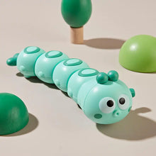 Mint green wind-up caterpillar toy with big eyes on a beige background