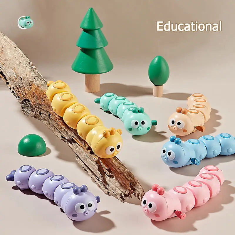 Colorful wind-up caterpillar toys crawling on driftwood with small toy trees