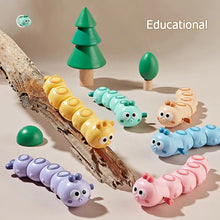 Colorful wind-up caterpillar toys crawling on driftwood with small toy trees