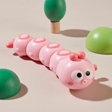 Pink wind-up caterpillar toy with a bow-shaped key on a beige background