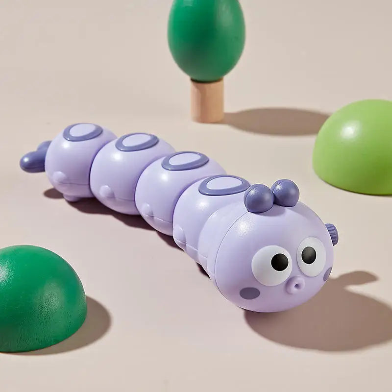 Purple wind-up caterpillar toy with big eyes on a beige background