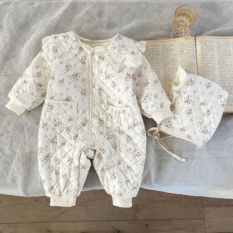 Winter floral romper and bonnet set styled on wood, a coordinated outfit for newborn gifting and cold-weather dressing.