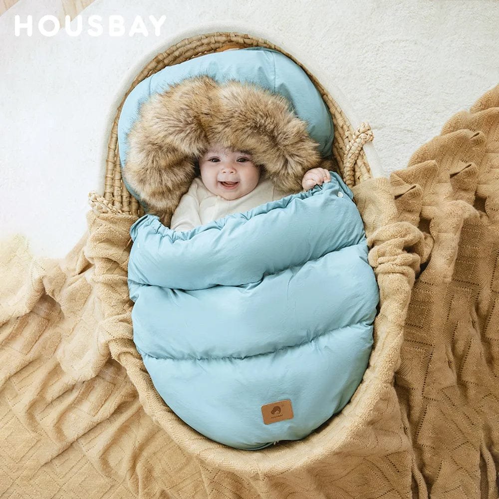 Newborn snuggled in the blue winter stroller sleeping bag with fur hood, offering full-body warmth for prams and car seats.