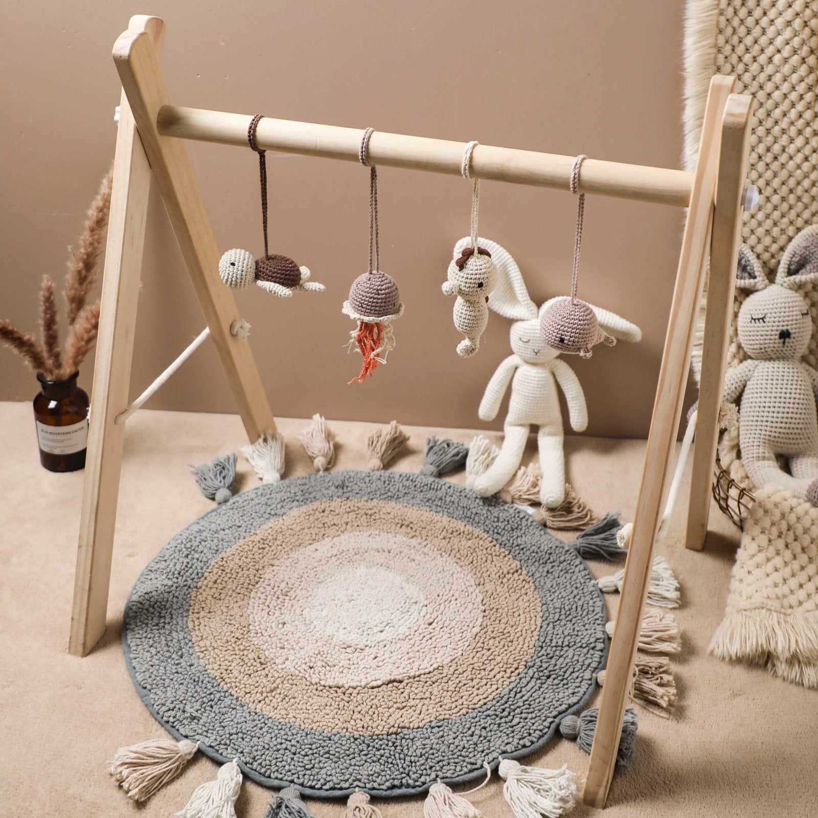 Wooden baby play gym frame styled with a round rug in a playroom, creating a soft space for infant floor play.