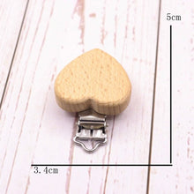 Heart shaped wooden pacifier clip with measurements, a beech teether holder that keeps soothers within reach at nap time.