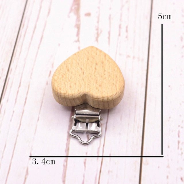 Heart shaped wooden pacifier clip with measurements, a beech teether holder that keeps soothers within reach at nap time.