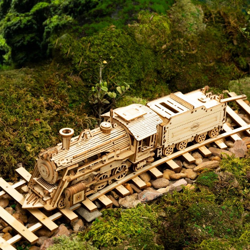 Wooden model train on a miniature track surrounded by greenery