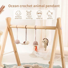 Close-up of an ocean crochet animal pendant on the wooden play gym, a soft toy for babies to bat and grasp.