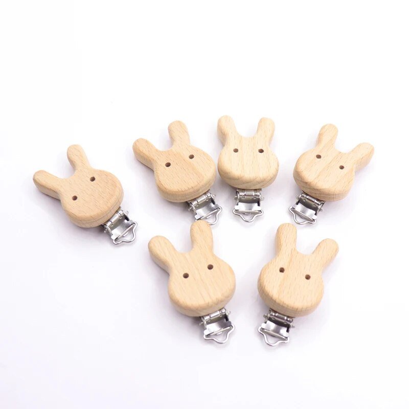 Six wooden rabbit shaped pacifier clips from the teether set, natural beech dummy holders that keep soothers clean during outings.