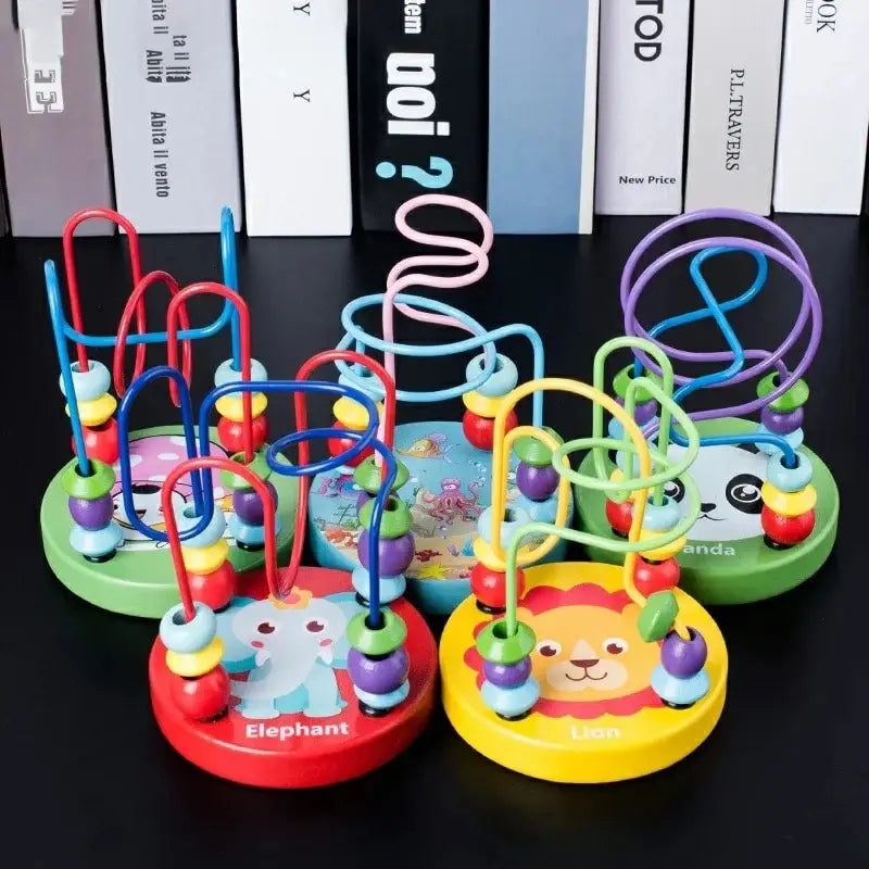 Six small wooden bead maze toys with animal bases in green, red, yellow and blue standing on a dark surface