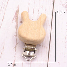 Wooden round pacifier clip with measurements on a light backdrop, a teether holder for checking size before everyday use.