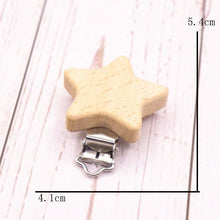 Star shaped wooden clip with metal clasp on a beech surface, a teether soother holder for daily nursery use.