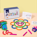 Iron puzzle box and cards beside a flower face built from colorful sticks, arcs and rings